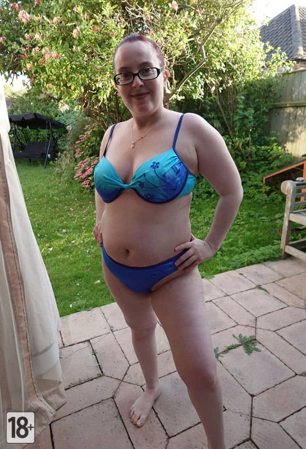 Толстая женщина с рыжими волосами в купальнике на дачном участке