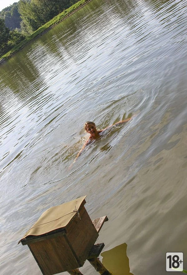 Фото: женщина-нудистка весело ныряет с тарзанки в озеро.